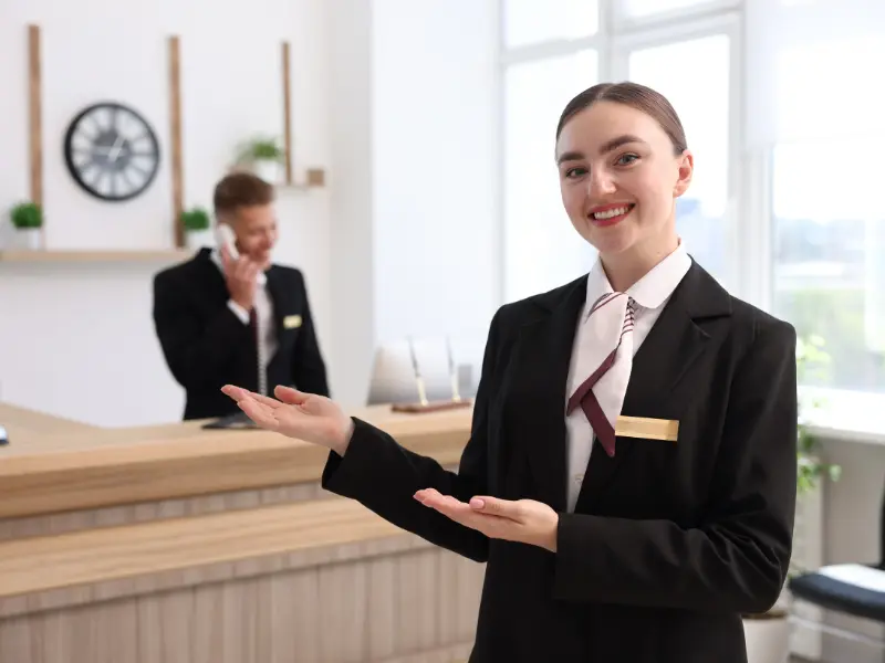 Réceptionniste accueillant un client international en anglais au front desk
